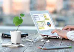 Workplace at Outdoor Patio and Hands of Person smart casual clothing typing on Laptop electronic Gadgets and color Pencils dropped around green Flower with Focus on plant leaves